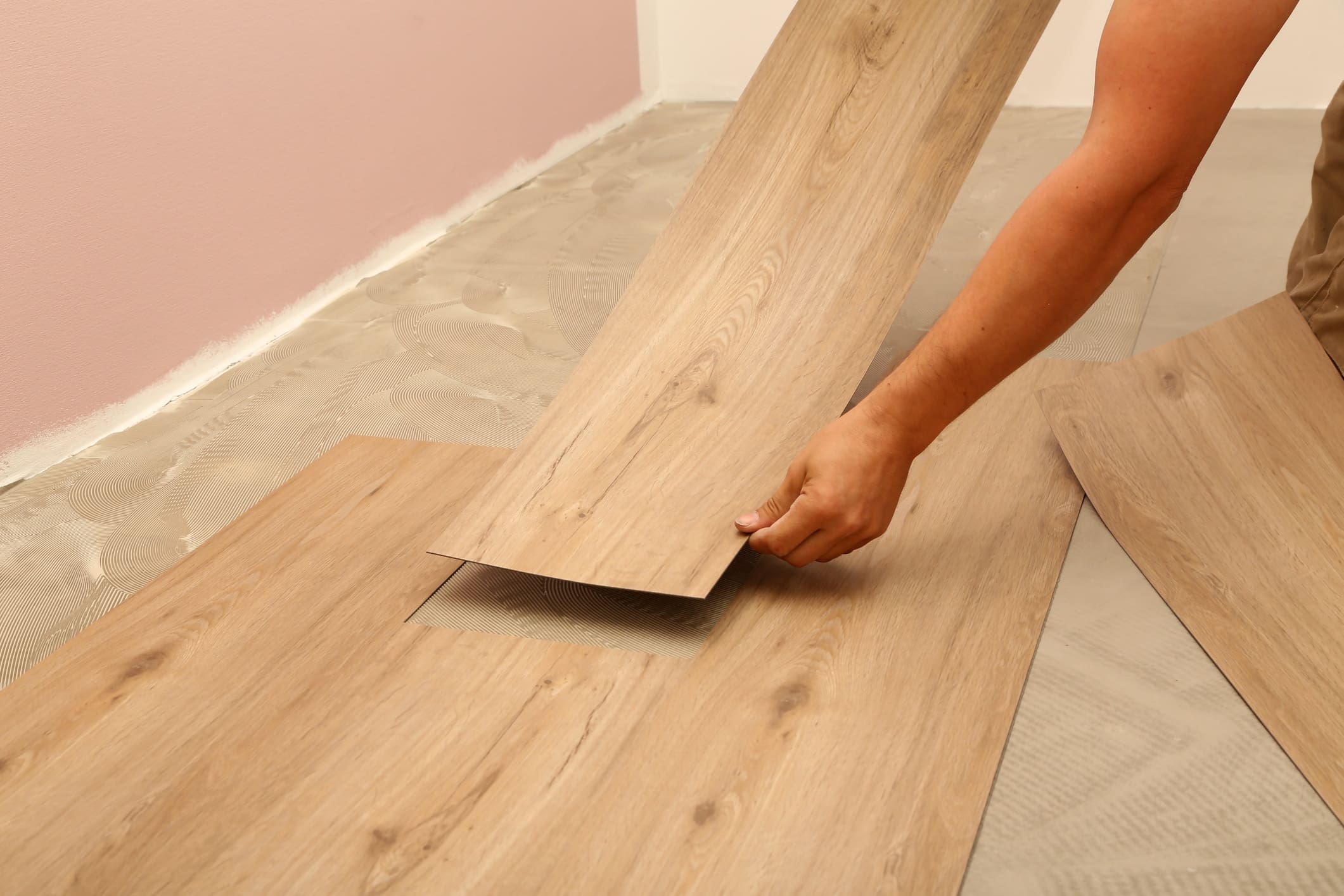 Worker installing new vinyl tile floor.